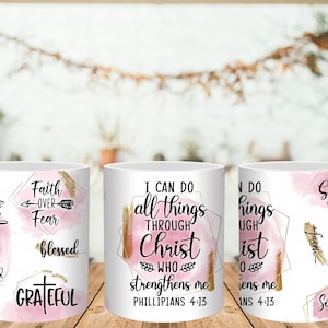 May include: White ceramic mugs with inspirational quotes and phrases in black script and gold accents. The mugs feature pink watercolor backgrounds and geometric shapes. Phrases include "Faith Over Fear" and "I Can Do All Things Through Christ."
