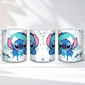 May include: White ceramic mug featuring a blue cartoon character with large ears and a blue and pink color scheme. The character is set against a blue and white background with floral accents. The mug has a handle.
