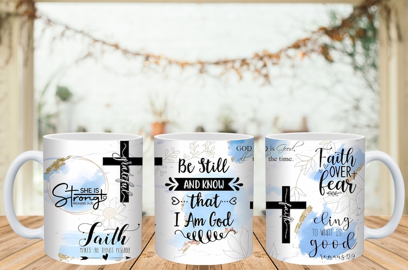 May include: White ceramic mugs with inspirational quotes and floral designs. Each mug features a black cross and text like "Strong," "Be Still," and "Faith Over Fear." The mugs have a light blue and gold color scheme.