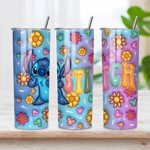May include: A cylindrical stainless steel tumbler with a lid and straw, featuring a blue and purple gradient background decorated with yellow and pink flowers, small mouse-ear silhouettes, a blue alien character, and the word STITCH in colorful letters.