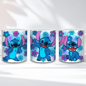 May include: Three white ceramic mugs featuring the character Stitch from Lilo & Stitch. Each mug has a different pose of Stitch, surrounded by blue and pink flowers against a blue watercolor background. The mugs are a fun and colorful item.