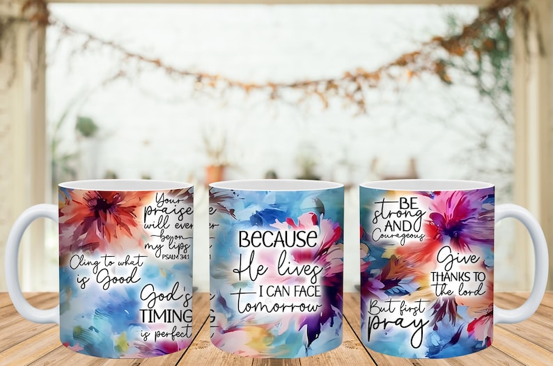 May include: Three white ceramic mugs with colorful floral designs and inspirational quotes. The mugs feature text like "Cling to what is Good" and "Because He lives I can face tomorrow."