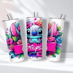 K&ouml;nnte beinhalten: Wei&szlig;er Becher mit einer Cartoonfigur mit gro&szlig;en Ohren, umgeben von rosa und blauen Blumen. Die Figur ist blau mit gro&szlig;en Augen und einem t&uuml;rkisfarbenen Bauch. Ein rosa Banner mit wei&szlig;em Text befindet sich unten.