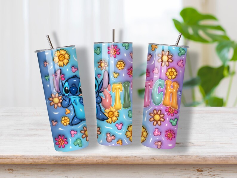 May include: Three cylindrical tumblers with metal straws featuring a blue and purple gradient background. The design includes a blue alien character, colorful flowers, small mouse-ear silhouettes, and the word STITCH in large, puffy, multi-colored letters.