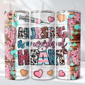May include: A set of three stainless steel tumblers with a floral and wood grain design. The tumblers feature the text "NURSING is a work of HEART" with a syringe and heart graphics. Pink flowers and hearts decorate the sides.
