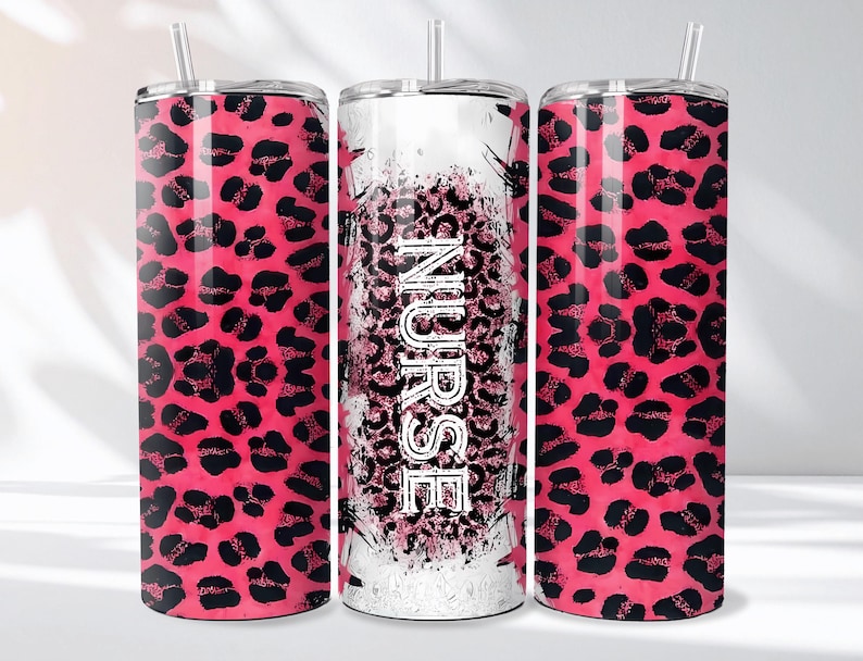 May include: Three stainless steel tumblers with lids and straws. Two tumblers feature a pink leopard print pattern. The center tumbler has the word "NURSE" in white, with a pink leopard print background.