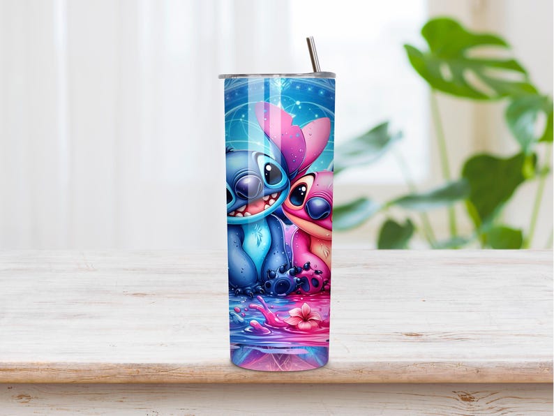 Puede incluir: Un vaso cil&iacute;ndrico de acero inoxidable con un estampado gr&aacute;fico vibrante de dos personajes alien&iacute;genas azules y rosas sentados juntos. El dise&ntilde;o incluye un fondo azul estrellado, una superficie de agua reflectante con salpicaduras y una pajita.
