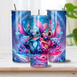 Puede incluir: Tres vasos cil&iacute;ndricos de metal con tapas y pajitas, que presentan un estampado gr&aacute;fico vibrante de personajes alien&iacute;genas azules y rosas rodeados de patrones c&oacute;smicos, salpicaduras de l&iacute;quido y efectos de luz brillantes en azul y magenta.