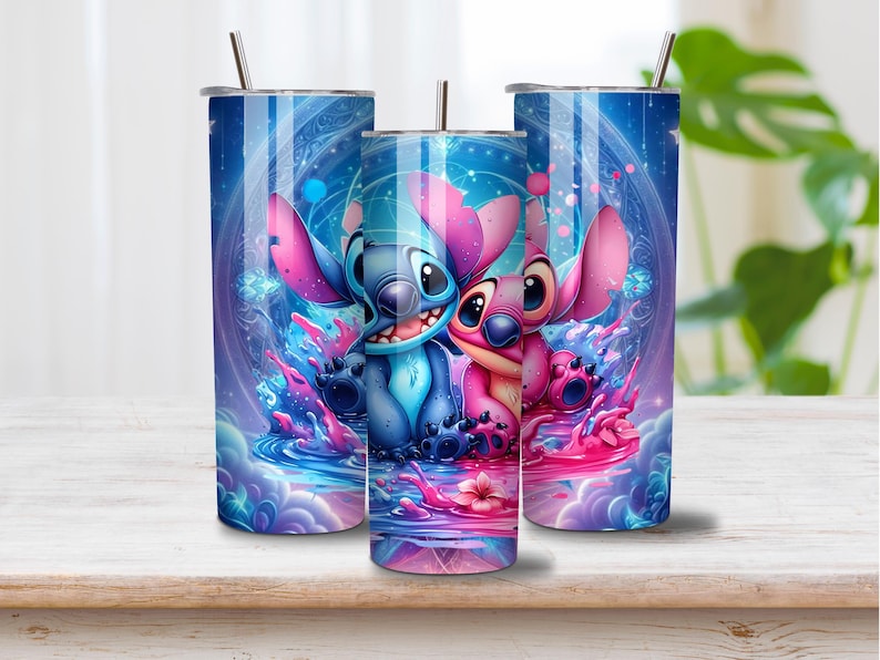 Puede incluir: Tres vasos cil&iacute;ndricos de metal con tapas y pajitas, que presentan un estampado gr&aacute;fico vibrante de personajes alien&iacute;genas azules y rosas rodeados de patrones c&oacute;smicos, salpicaduras de l&iacute;quido y efectos de luz brillantes en azul y magenta.
