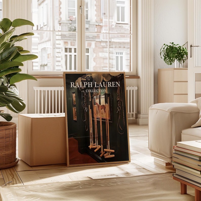 Op de afbeelding: Een ingelijste "Ralph Lauren Collection" print met een donkergroene interieursc&egrave;ne met paardensportuitrusting en een schilderij van een paard. De print staat op een houten vloer, naast een beige kubus en een potplant.