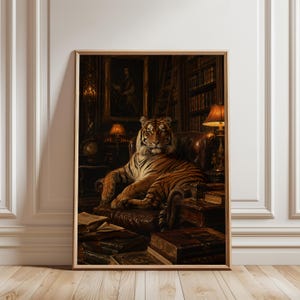 May include: A framed wall art print depicting a tiger sitting on a dark brown leather armchair within a dimly lit library. The scene includes stacks of old books, a table lamp, and a framed portrait on the wall, all rendered in warm, dark tones.