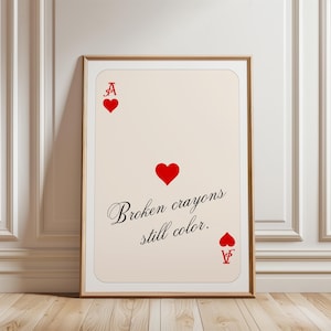 Könnte beinhalten: Ein rechteckiger Wandkunstdruck mit einem Herz-Ass-Spielkartendesign auf cremefarbenem Hintergrund. Der Druck zeigt ein rotes Herzsymbol, den Buchstaben A und den schwarzen kursiven Text "Broken crayons still color." in der Mitte.