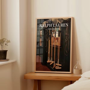 Op de afbeelding: Een ingelijste print van de Ralph Lauren Collection met paardensportuitrusting en een schilderij van een paard. De print staat op een houten tafel, met een kleine plant en een glazen fles. De afbeelding heeft een warme, uitnodigende uitstraling.