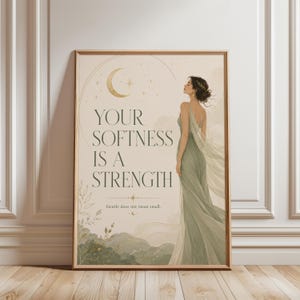 Può includere: Una stampa artistica rettangolare da parete con una figura in abito verde salvia, una mezzaluna dorata e il testo: YOUR SOFTNESS IS A STRENGTH. Sotto, un testo più piccolo recita: Gentle does not mean small. Lo sfondo è color crema.