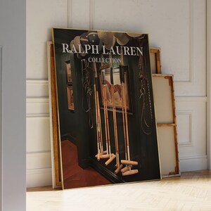 Op de afbeelding: Een ingelijste print van de Ralph Lauren Collection met een paardenschilderij, polomallen en paardensportuitrusting. De print heeft een gouden lijst en staat tegen een muur. De tekst "RALPH LAUREN COLLECTION" is zichtbaar.