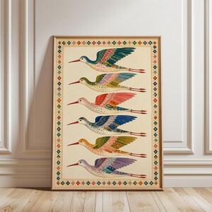 May include: A framed vertical print featuring six stylised birds in flight, arranged in a column. Each bird has a speckled body, a long thin red beak, and multicoloured wings in shades of teal, pink, blue, orange, and purple, enclosed by a geometric border.
