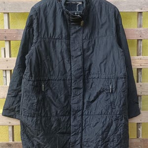 May include: Black quilted jacket with a stand-up collar and a zipper closure. The jacket has two front pockets and a subtle pattern. The brand name "BALMAIN" is visible on the hanger.