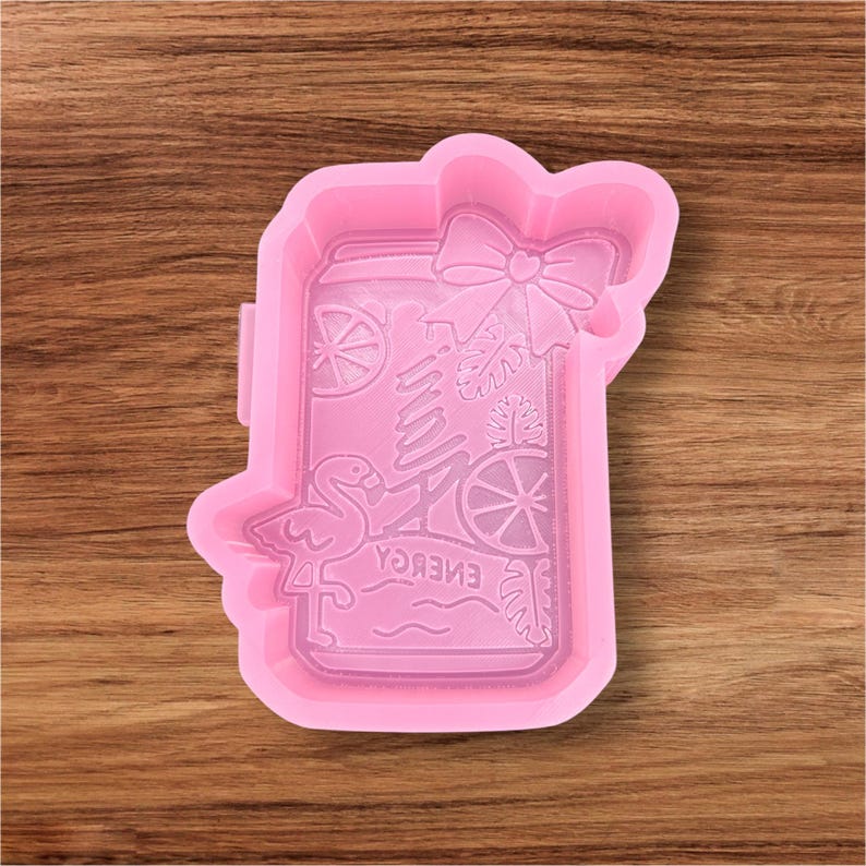 May include: A pink silicone mould in the shape of a jar, featuring a bow, flamingo, and tropical fruit designs. The word "ENERGY" is printed in reverse inside the jar. The mould is for crafting.