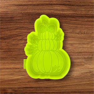 May include: A bright green silicone mold in the shape of a stacked pumpkin. The mold features three pumpkins of varying sizes, with a bow and leaves on top. The mold is designed for crafting or baking seasonal treats.