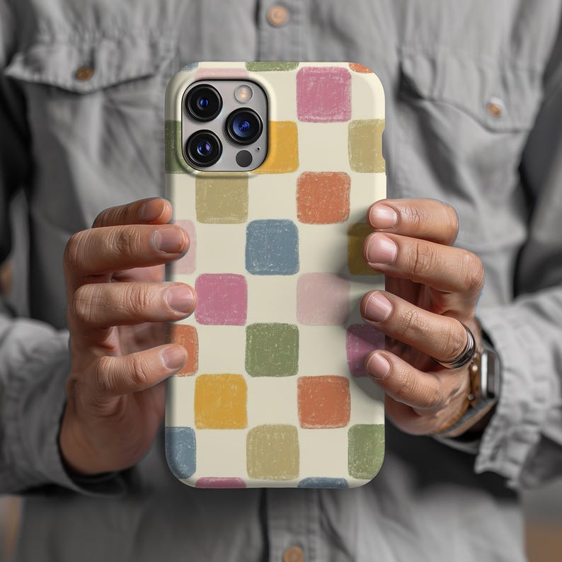 May include: A phone case with a cream-colored background and a repeating pattern of colorful squares in shades of blue, pink, green, orange, and yellow. The case has a camera cutout and button placements.