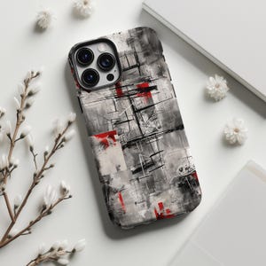 Könnte beinhalten: Eine Smartphone-Hülle mit einem abstrakten Design, bestehend aus einem graustufigen Hintergrund, schwarzen, tuscheartigen Pinselstrichen und verstreuten, leuchtend roten rechteckigen Akzenten. Die Hülle hat eine Aussparung für eine Dreifachkamera.