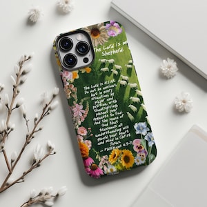May include: A phone case featuring a floral design with text from Philippians 4:5-7. The case has a green background with sheep and the words "The Lord is my Shepherd." Colorful flowers and text surround the case.