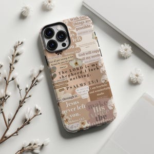 May include: A beige and brown phone case with a collage design featuring floral accents and religious text. The case includes phrases like "The LORD is my shepherd, I lack nothing" and "Jesus never left you."
