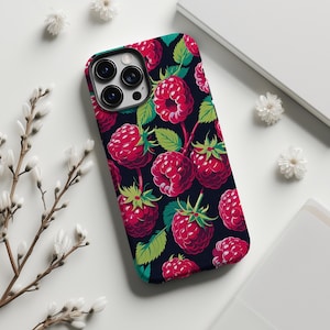 Puede incluir: Funda de teléfono con un patrón de frambuesas rojas y hojas verdes sobre un fondo oscuro. La funda tiene un borde negro y ofrece una protección elegante para el dispositivo.