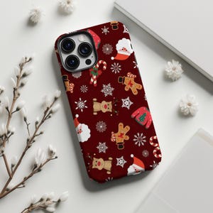 以下が含まれることがあります： クリスマス柄のバーガンディ色のスマホケース。サンタクロース、トナカイ、ジンジャーブレッドマン、雪の結晶、キャンディケーン、クリスマスセーターのデザイン。スマートフォンに合うように設計されています。