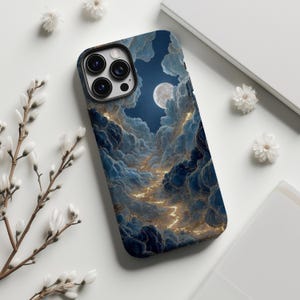 Pode incluir: Capa de telemóvel com um design celestial com uma lua cheia, nuvens e um caminho de luz dourada. A capa tem um esquema de cores azul escuro e dourado, com um acabamento brilhante. Flores brancas e um fundo branco rodeiam a capa.