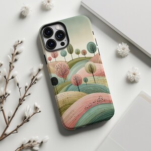 May include: A phone case featuring a watercolor landscape design with rolling hills, trees, and a soft color palette of pink, green, and beige. The case has a black border and a camera cutout.