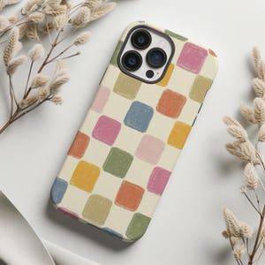 May include: A phone case with a cream-colored background and a pattern of colorful, square shapes in shades of blue, pink, orange, yellow, and green. The case has a camera cutout and a black border.