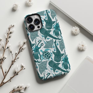 Puede incluir: Una funda de teléfono turquesa y blanca con un patrón repetido de criaturas marinas, incluyendo tiburones ballena, pulpos y mantarrayas. La funda está hecha de un material duradero y tiene un recorte para la cámara.