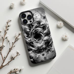 May include: A black and white phone case featuring a swirling vortex of skulls and ghostly figures. The case has a black border and a glossy finish. The design is detailed and artistic, creating a spooky and gothic aesthetic.