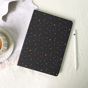 May include: Black tablet case with a colorful star pattern. The case has a sleek design and is accompanied by a white stylus. The stars are in shades of pink, yellow, blue, and orange.