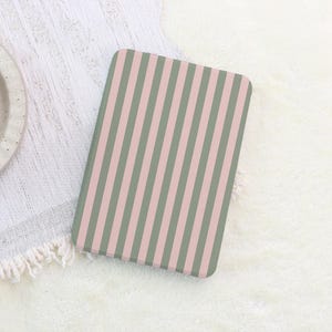 May include: A rectangular object with a vertical striped pattern in muted pink and green. The object is set against a white, textured background. The stripes are evenly spaced and run the length of the object.