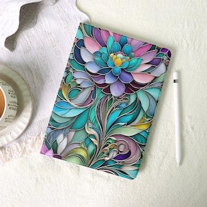 May include: A tablet case with a colorful floral design. The case features a large flower with blue, purple, and pink petals, surrounded by green and teal leaves. The design has a stained glass effect with gold outlines. A white stylus rests beside the case.