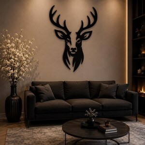 Può includere: Decorazione murale in metallo nero a forma di testa di cervo in un soggiorno. Un divano grigio scuro con cuscini è sotto l'opera d'arte. Un tavolino rotondo e un vaso con fiori bianchi sono anch'essi presenti. Design moderno e minimalista.
