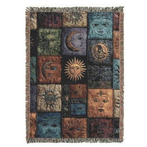 May include: Woven throw blanket featuring a patchwork design of celestial faces, including suns, moons, and human-like visages. The squares are in shades of blue, brown, green, and gold, with a fringed edge. The blanket is a decorative home textile.
