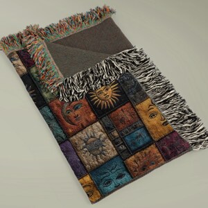 May include: A decorative throw blanket featuring a patchwork design with embroidered sun and moon faces in various colors. The blanket has a dark gray backing and colorful fringe trim.