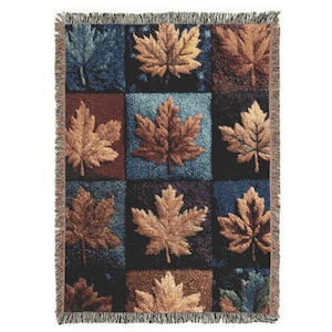 Może przedstawiać: Tkany koc z powtarzającym się wzorem liści klonu w odcieniach brązu, złota i niebieskiego. Liście są umieszczone na patchworkowym tle w różnych kolorach. Koc ma frędzelkową krawędź.