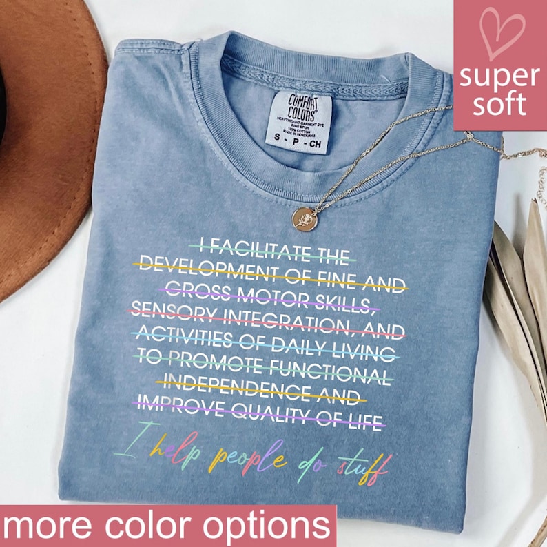 May include: A blue Comfort Colors t-shirt with the text "I facilitate the development of fine and gross motor skills... I help people do stuff." A gold necklace with a pendant is on the shirt. The words "super soft" are in a pink box.