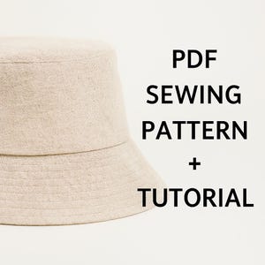 May include: A beige bucket hat made from a textured fabric. The hat is set against a white backdrop. The text on the right side of the hat reads "PDF SEWING PATTERN + TUTORIAL".