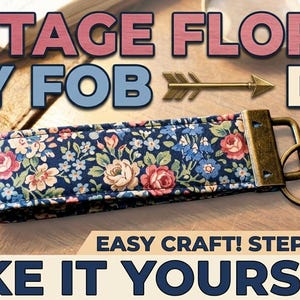 May include: A vintage floral key fob with a navy blue background and a pattern of pink and blue flowers. The key fob has a bronze-colored metal ring and hardware. The image includes the text "VINTAGE FLORAL KEY FOB DIY! EASY CRAFT! STEP-BY-STEP MAKE IT YOURSELF!"