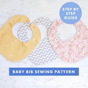 May include: Three baby bibs in yellow with white polka dots, gray chevron, and pink floral patterns. The bibs are arranged on a white surface. Text reads "Baby Bib Sewing Pattern" and "Step by Step Guide".