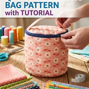 May include: A quilted cosmetic bag pattern with tutorial. The cylindrical bag is peach-colored with a white floral pattern and a navy blue zipper. The image includes sewing supplies like thread spools, fabric, scissors, and pencils with inspirational quotes.