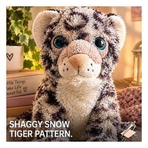 Puede incluir: Un peluche con un patrón de tigre de las nieves peludo, con pelaje blanco y gris oscuro, grandes ojos verde azulado y una nariz de color tostado claro. El texto SHAGGY SNOW TIGER PATTERN está impreso en blanco en la esquina inferior izquierda.