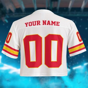 May include: White mesh jersey with red numbers "00" and red text "YOUR NAME" on the back. The sleeves have red and yellow stripes. The jersey is a cropped style.