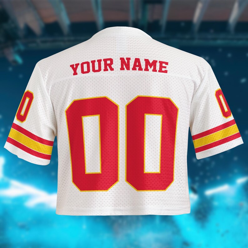 May include: White mesh jersey with red numbers "00" and red text "YOUR NAME" on the back. The sleeves have red and yellow stripes. The jersey is a cropped style.