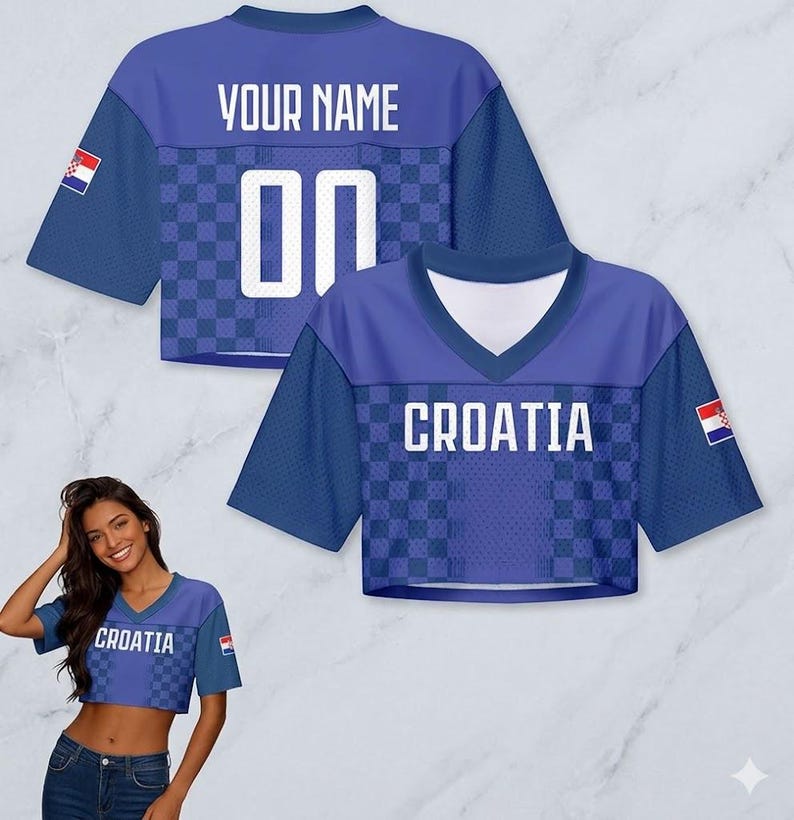 May include: Blue crop top jersey with the word "CROATIA" and the Croatian flag. The jersey has a checkered pattern and the text "YOUR NAME" and the number "00" on the back. The jersey has short sleeves.